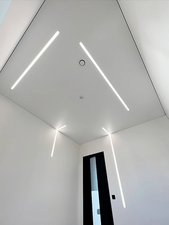 Натяжной потолок со световыми линиями, которые переходят на стену